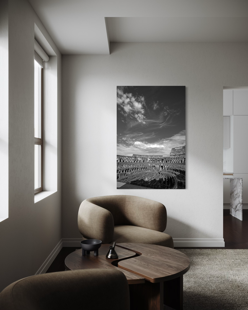 Black-and-white photography on canvas of the Colosseum in Rome, showing its curved arches and open arena beneath a dramatic sky.