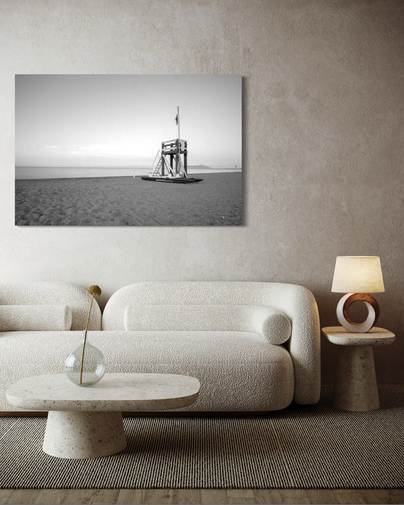 Black-and-white photography on canvas of a solitary lifeguard tower on a quiet beach, with horizon, sea, and a sense of calm.