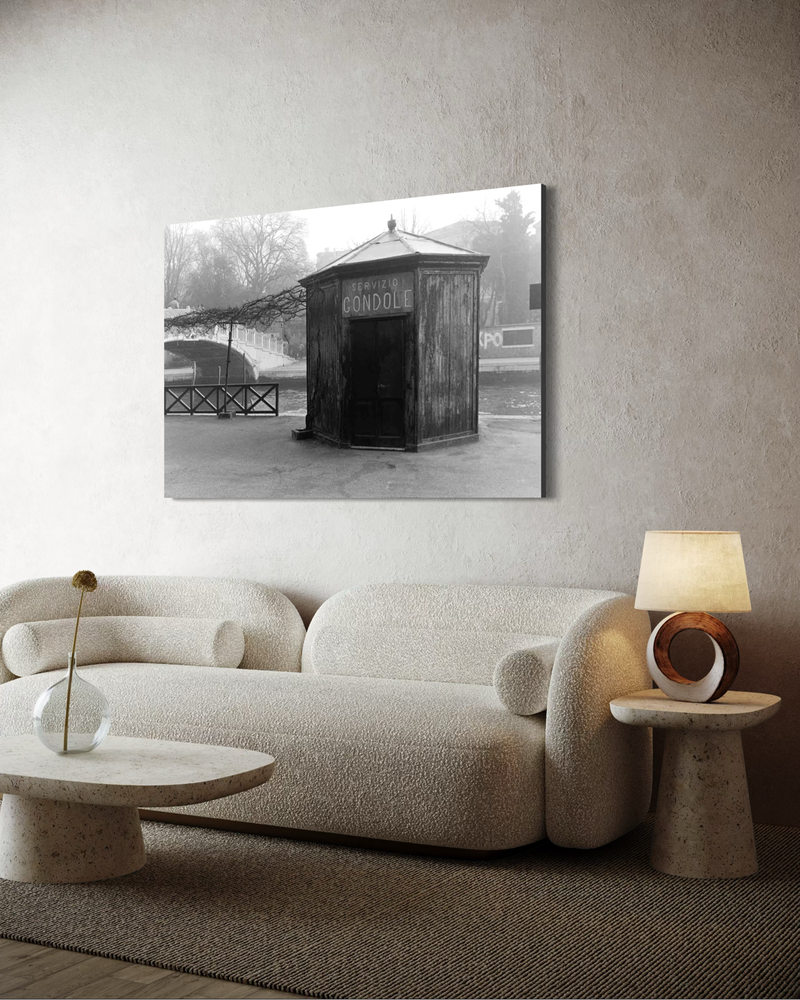 Black-and-white photography on canvas of a small wooden structure marked “Servizio Gondole” by a canal, surrounded by mist and stillness.
